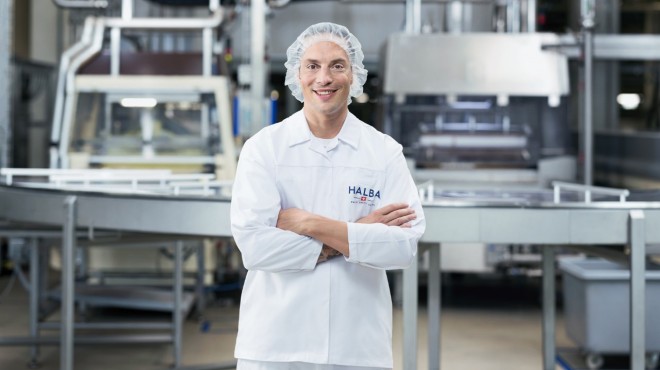 Un employé du service de production du fabricant de chocolat Halba sourit à la caméra.